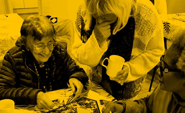 Two ladies leaning over a puzzle