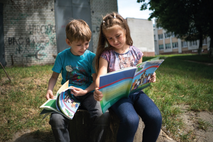 Boy and girl sitting together reading a book