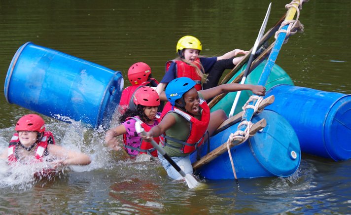 young people in life jackets falling off raft