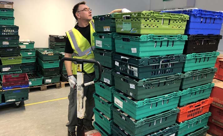 man at food bank with stacked boxes