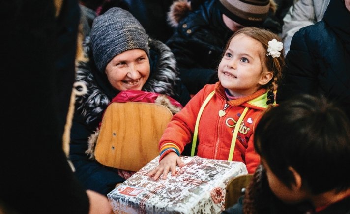 Elderly lady and child smiling and receiving a Christmas shoebox