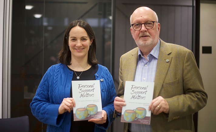 Claire Niclasen and Myles Wilson holding copies of their book Personal Support Matters