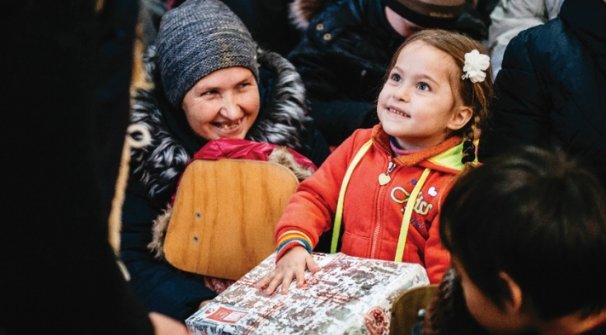 Elderly lady and child smiling and receiving a Christmas shoebox